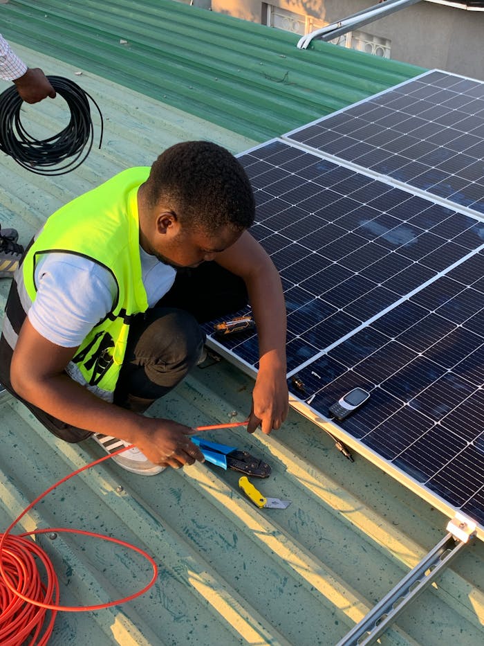 contact-img Technician working on solar panel installation with cables and tools on a sunny day.