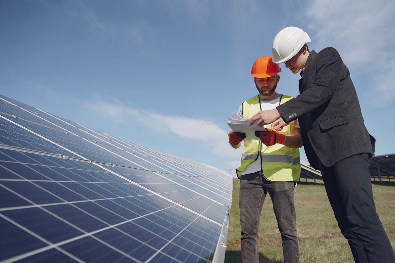 gallery-2 Low angle of young inspector and foreman in hardhats checking documentation against modern solar panels in field