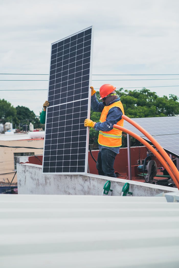 gallery-6 A technician in safety gear installs a solar panel on a rooftop, promoting renewable energy.