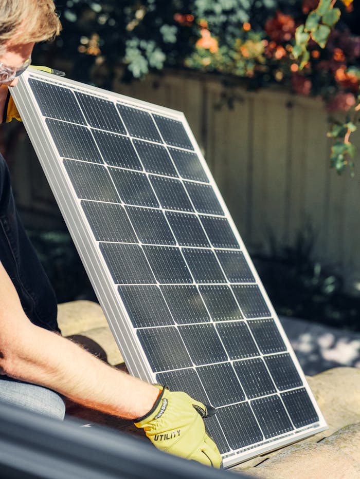 gallery-5 A worker installs a solar panel in a garden, promoting clean energy.