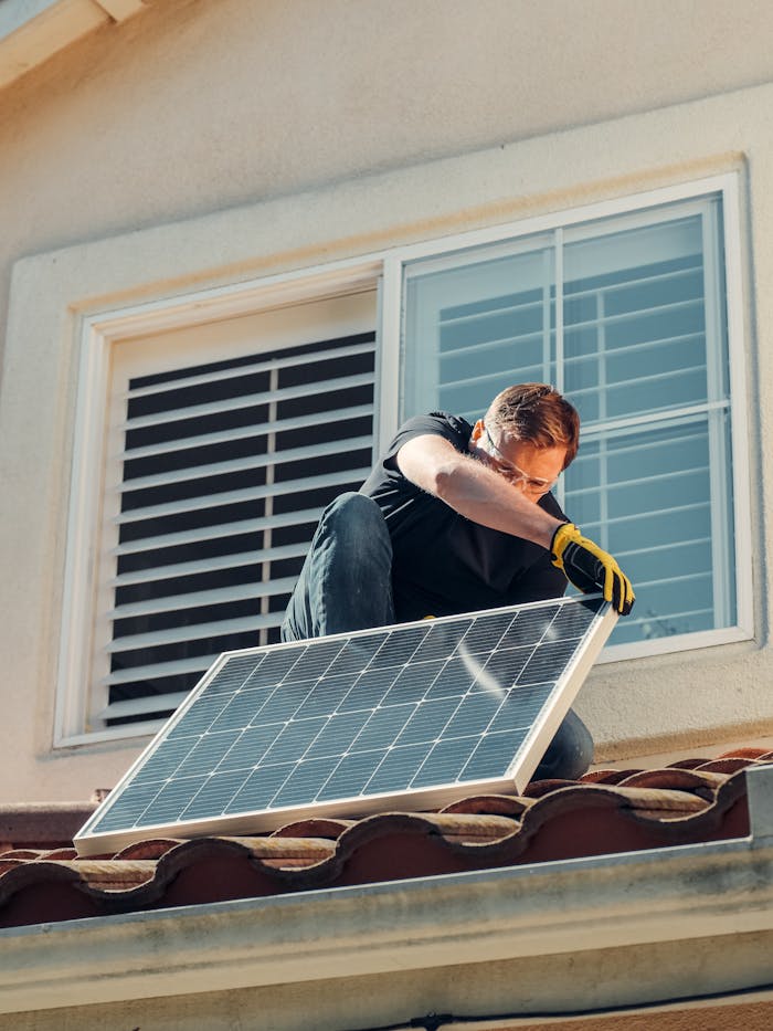 services-01 Man installing a solar panel on a residential rooftop, promoting sustainable energy.