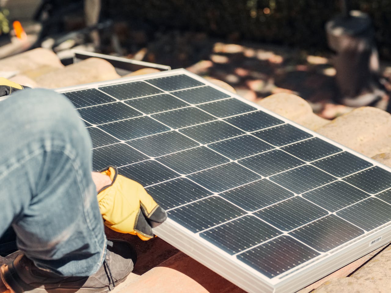 why-choose-us A worker installs a solar panel on a sunlit rooftop, exemplifying renewable energy.