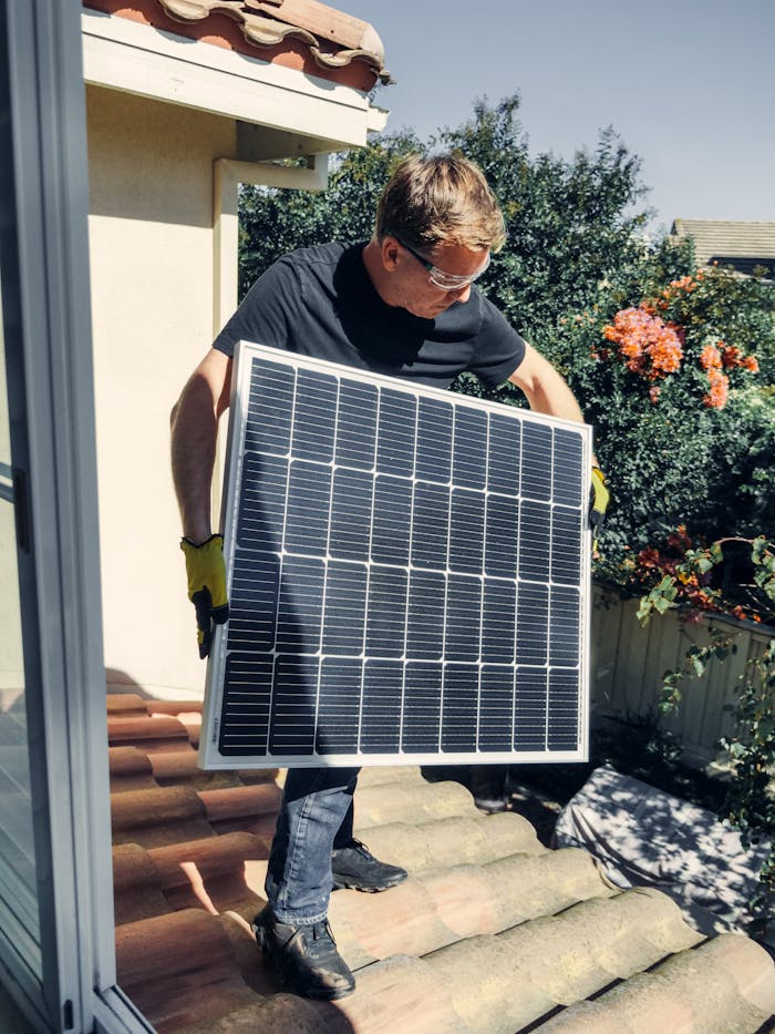 gallery-4 A worker installs a solar panel on a roof, promoting clean and renewable energy.