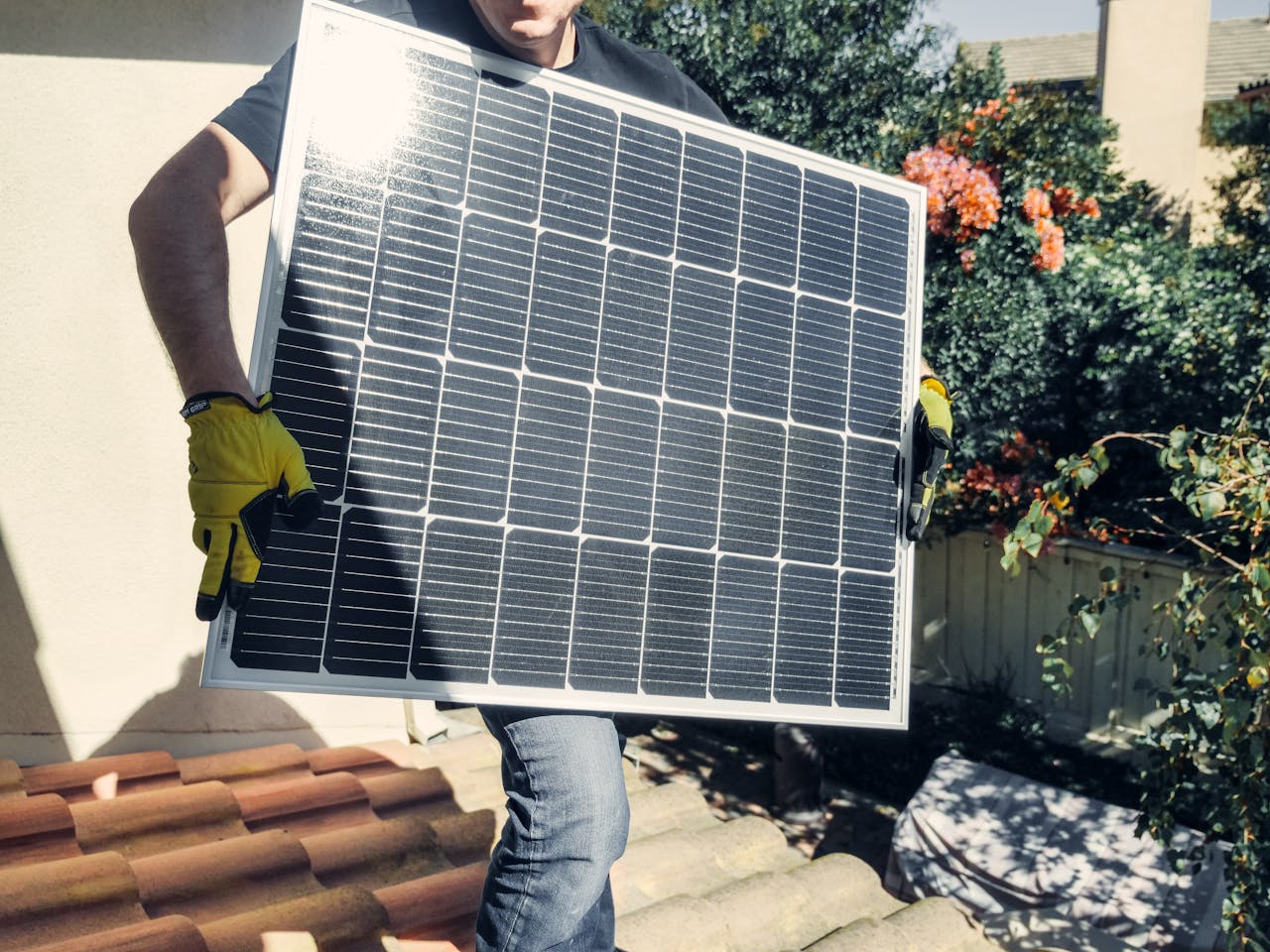 gallery-1 Technician carrying solar panel on rooftop. Clean energy installation outdoors.